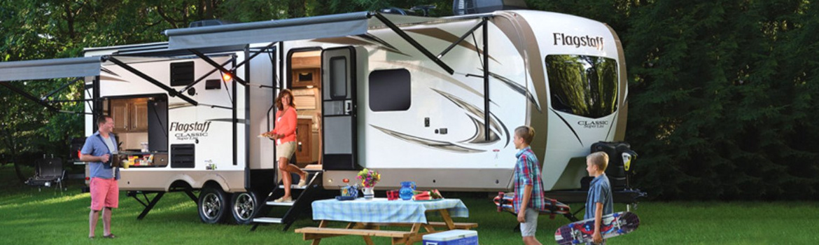 A family spending time together next to a 2018 Flagstaff Classic RV on a camp ground.